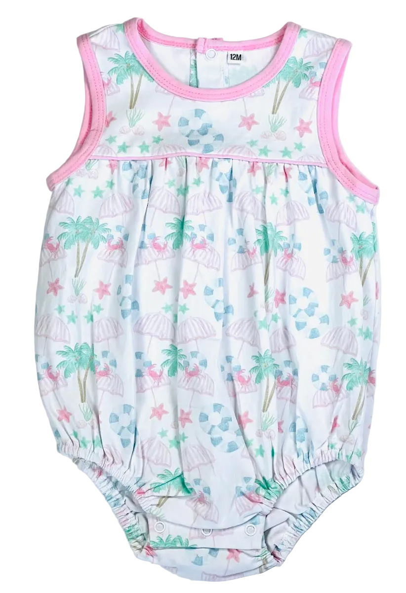 A baby sleeveless romper with a white background featuring a tropical print of palm trees, beach umbrellas, starfish, and blue waves, finished with pink trim.